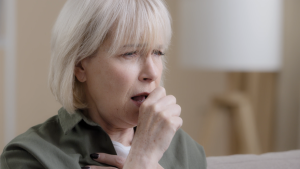 Woman coughing in promotional image for lung cancer awareness