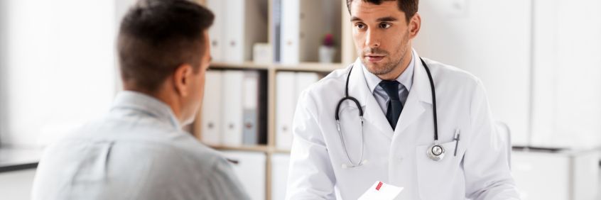 Male patient taking a referral for an Central Queensland Radiology scan from his doctor in a white coat with stethoscope