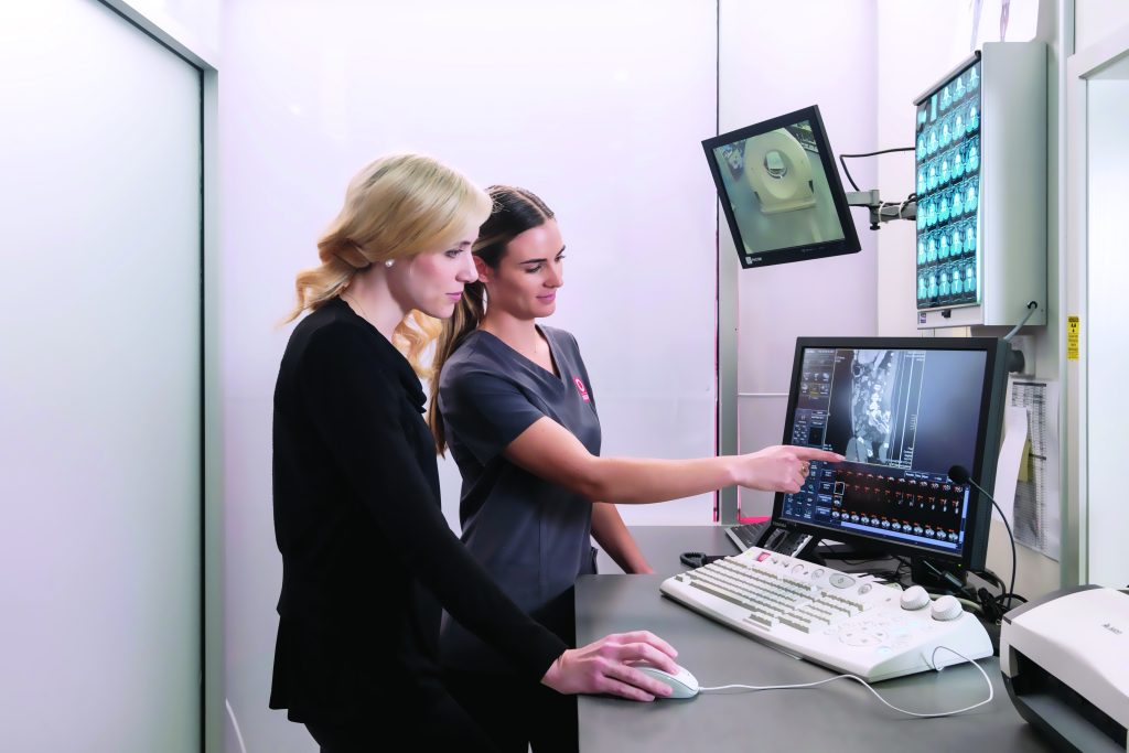 MRI technician discussing an MRI scan with a radiologist pointing at image on screen