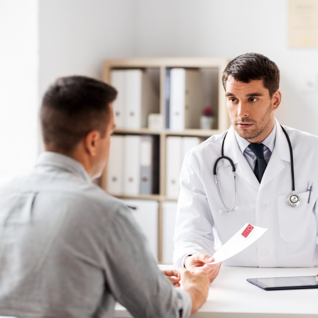 Doctor in white coat handing patient in grey shirt a referral to Central Queensland Radiology